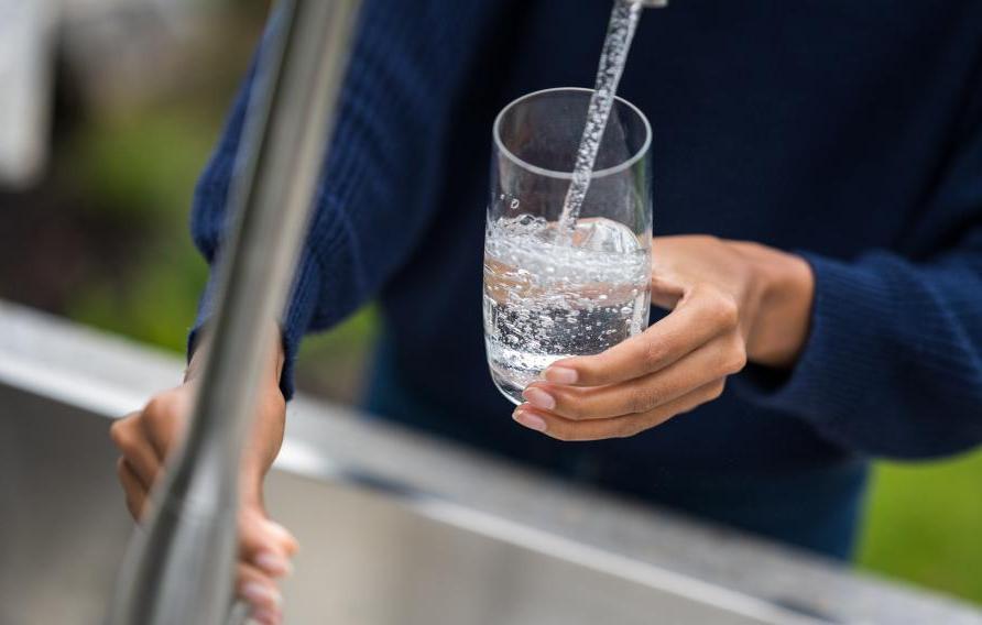 Woman's hands filling glass with water stock photo